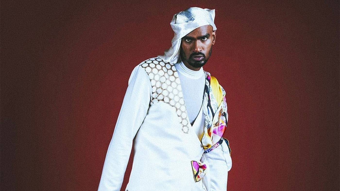 Shan Vincent de Paul wearing a bold white outfit and Cult Luxury silk scarf, featured in Rolling Stone. Showcasing vibrant design and modern luxury fashion