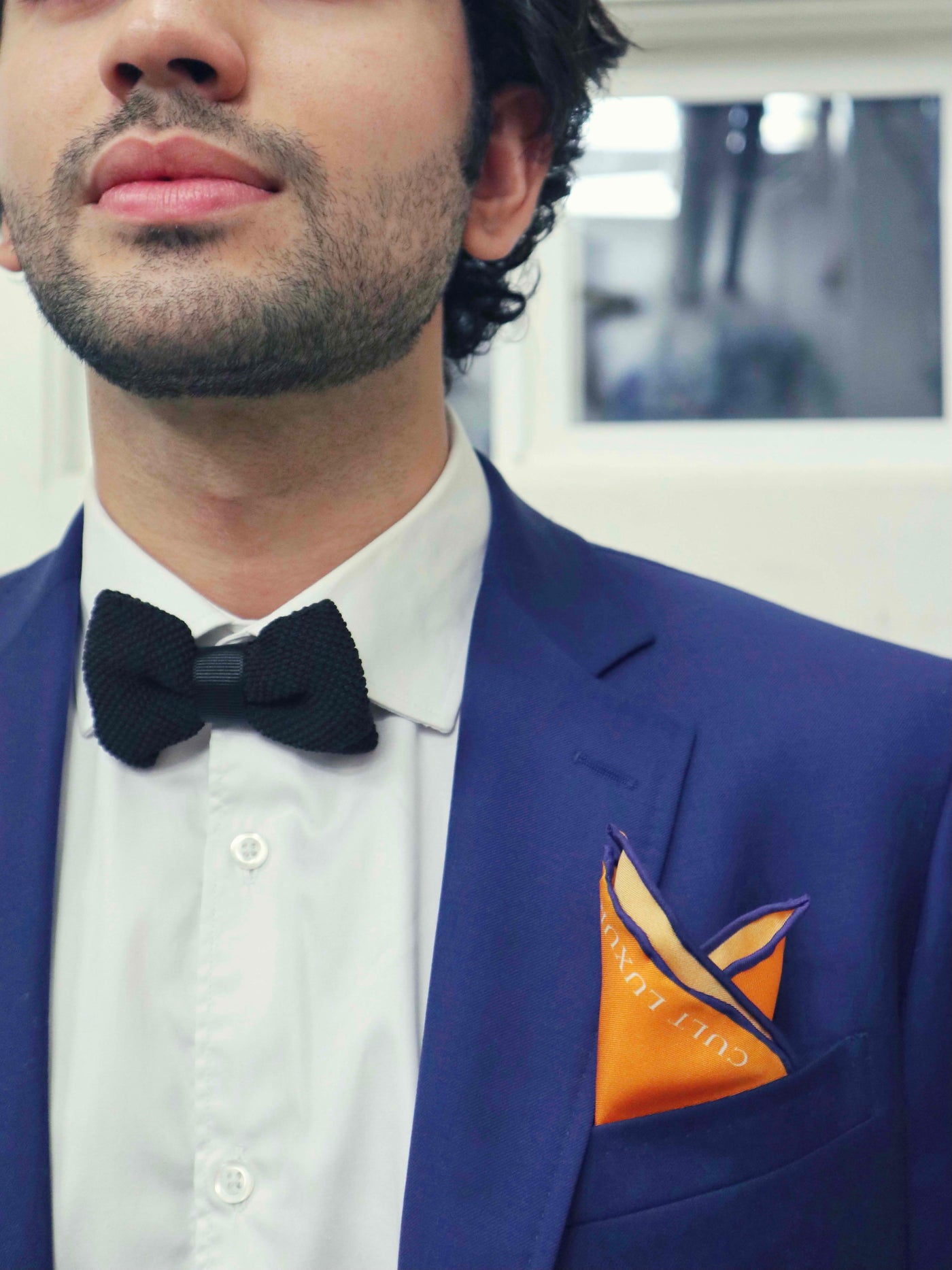 Bold orange silk pocket square styled in a blue suit pocket, adding a refined pop of color to formalwear.