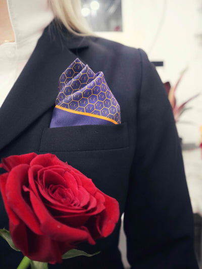 Royal blue silk pocket square styled elegantly in a suit jacket pocket with a red rose accent, adding sophistication to any formal attire.