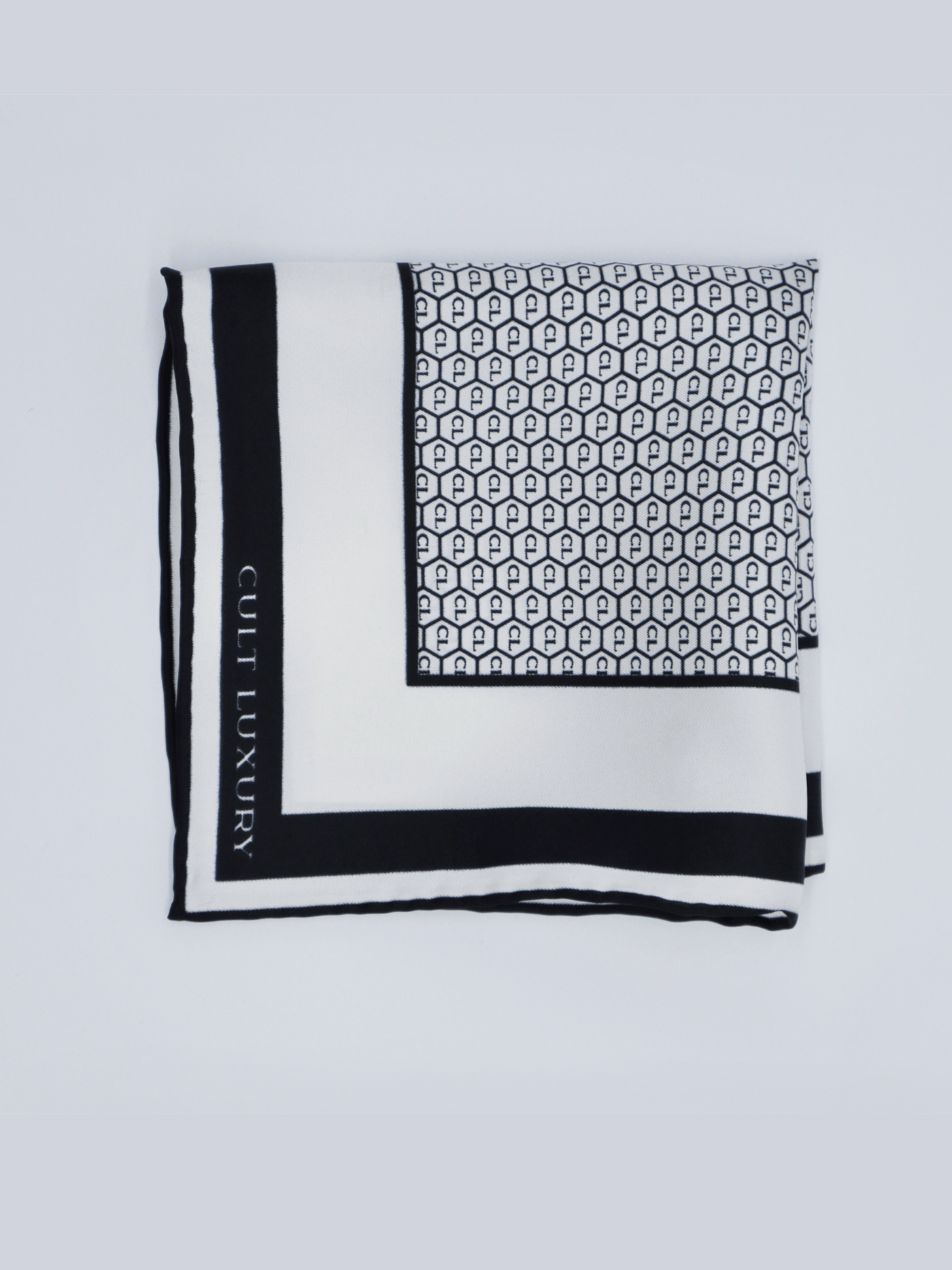 White silk pocket square folded to showcase Cult Luxury’s minimal design and signature monogram print.