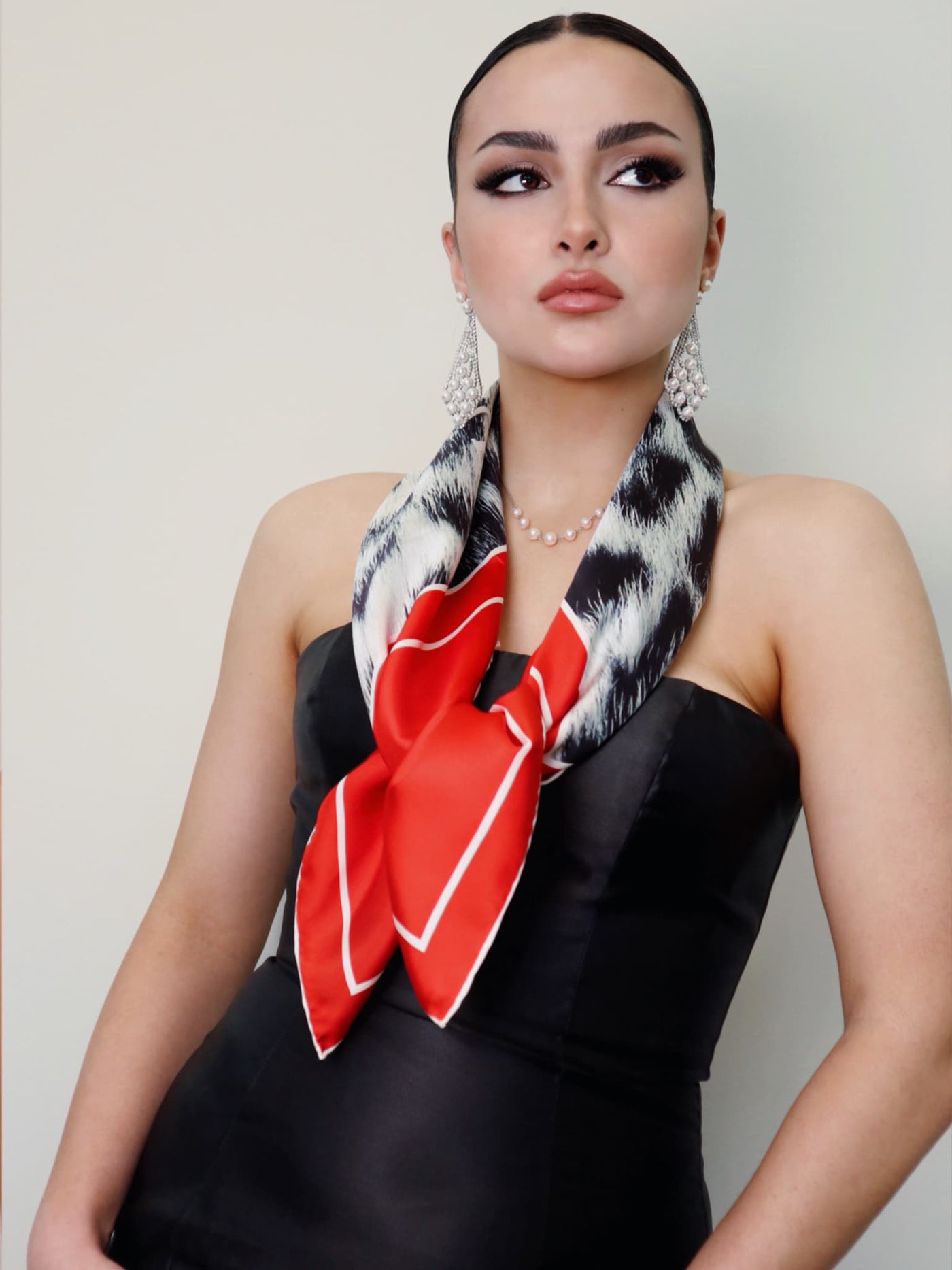 Model wearing the Red Snow Leopard 90 scarf tied at the front, featuring red borders and a snow leopard pattern from Cult Luxury.