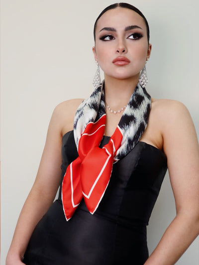 Model wearing the Red Snow Leopard 90 scarf tied at the front, featuring red borders and a snow leopard pattern from Cult Luxury.