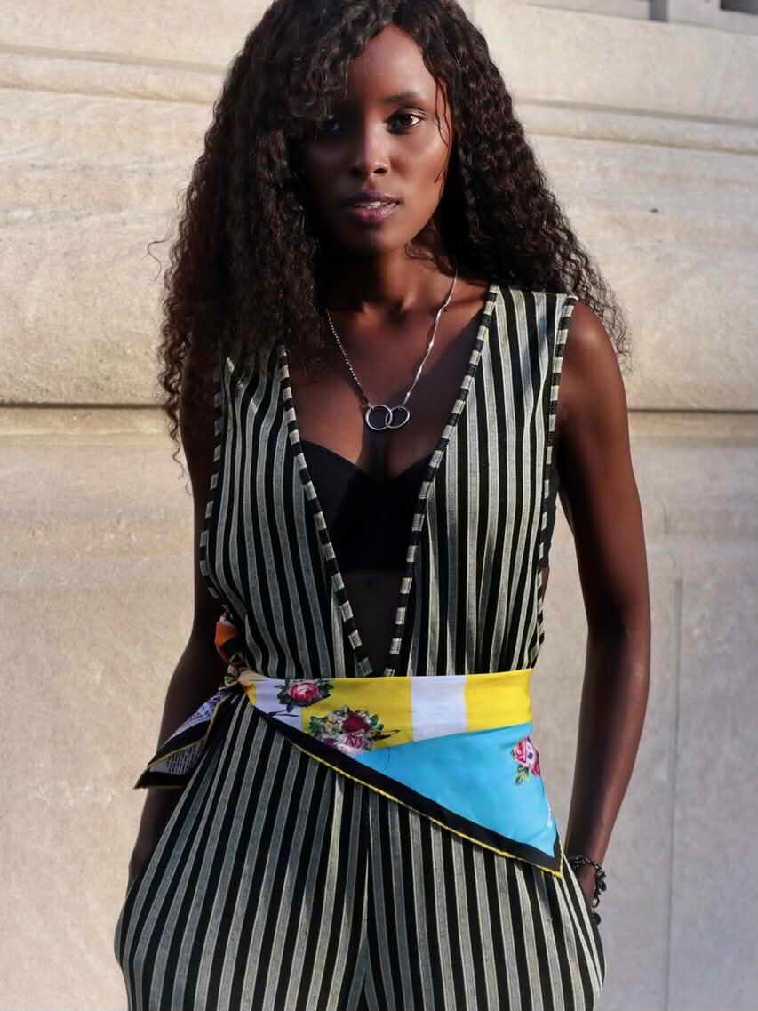 Model wearing the Beloved Armor silk scarf 65 tied as a statement waist belt, showcasing Cult Luxury’s vibrant yellow, blue, and floral design against bold stripes