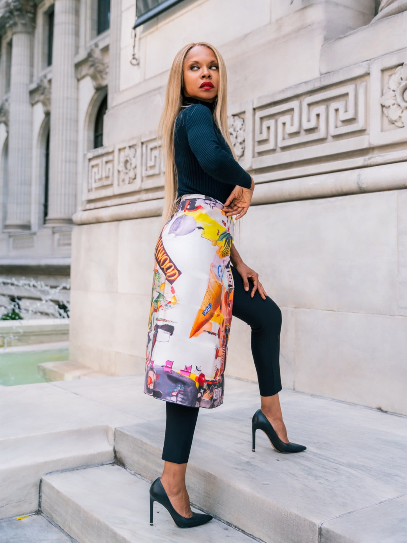 Cult Luxury Hollywood Hills 90 silk scarf styled as a skirt on the model, showing off its vivid collage design with pops of color and artistic elements that evoke Hollywood’s iconic edge.