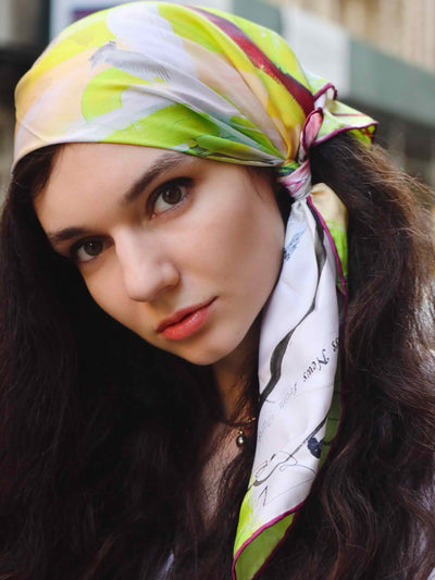 Hand-rolled silk scarf 65, styled elegantly as a headscarf on a model, showcasing the vivid abstract print of the Medicine for Regret luxury silk scarf